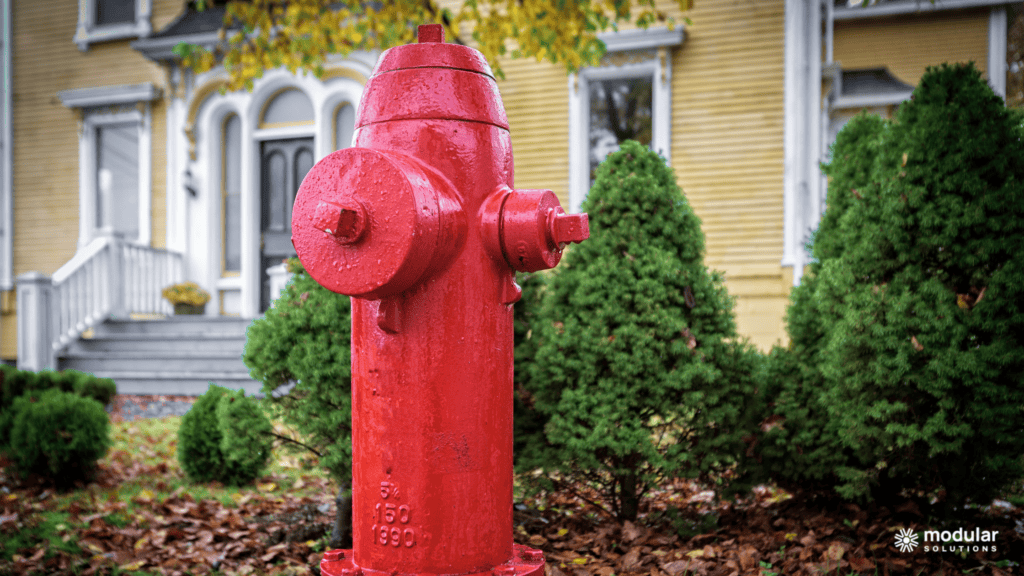A red fire hydrant in the foreground of a home.